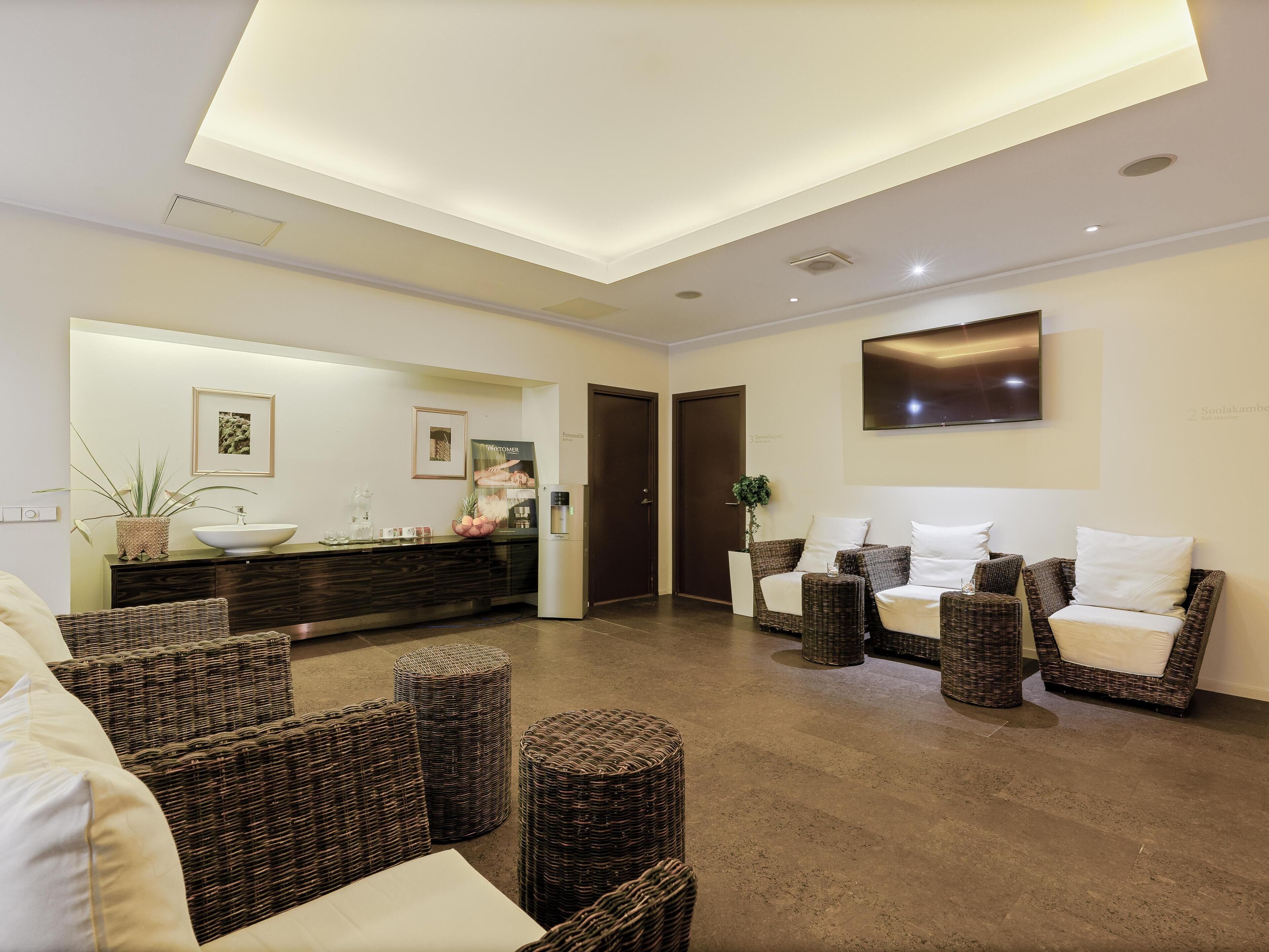 A modern lobby with a reception desk, seating area, and a large TV screen.