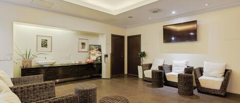 A modern lobby with a reception desk, seating area, and a large TV screen.