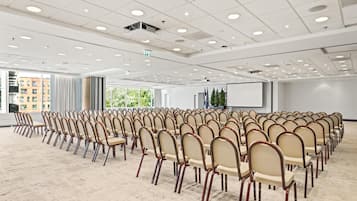 A conference room with rows of chairs, a projector screen, and large windows.