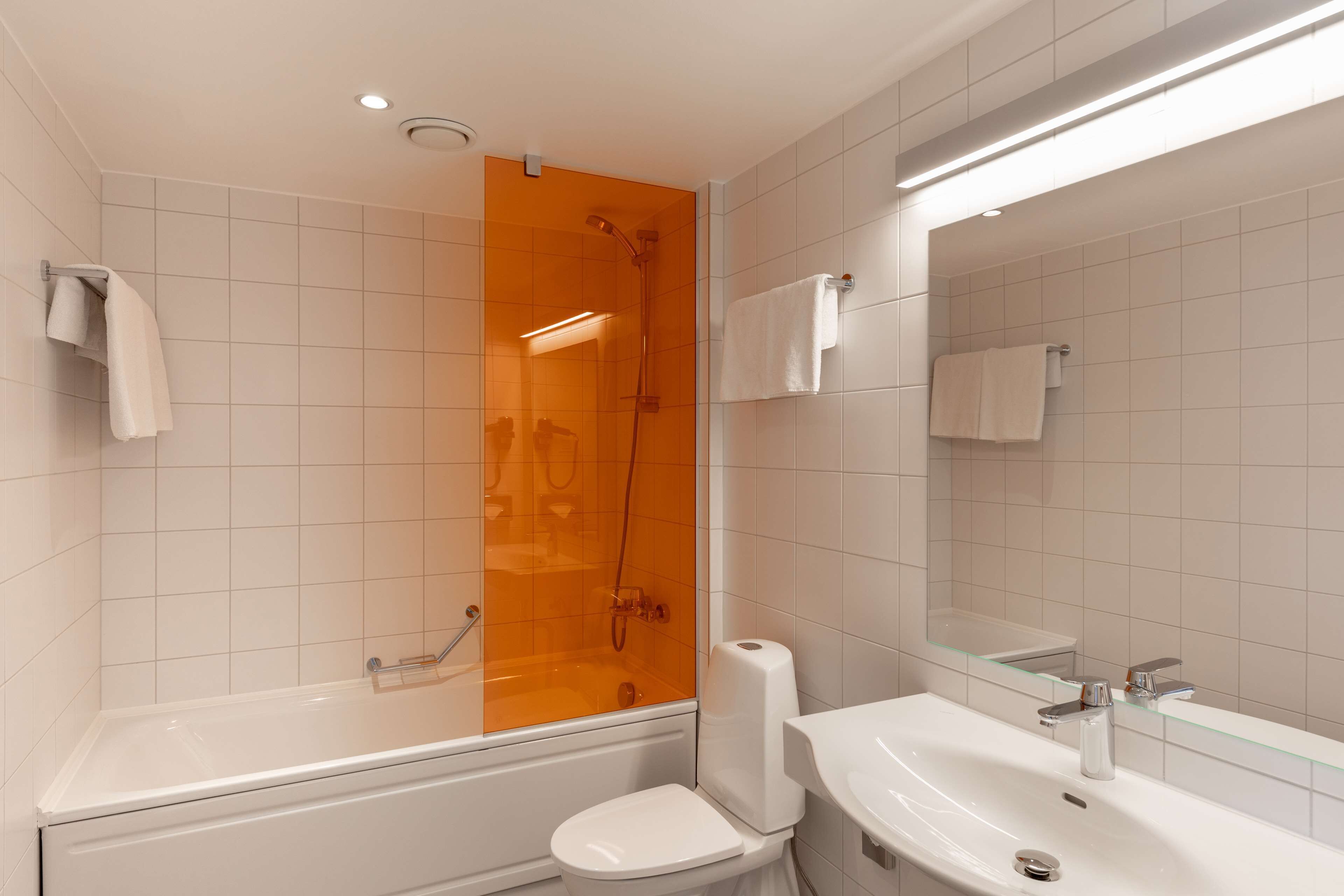 A modern bathroom with a glass-enclosed shower, a white bathtub, a white toilet, and a white sink.