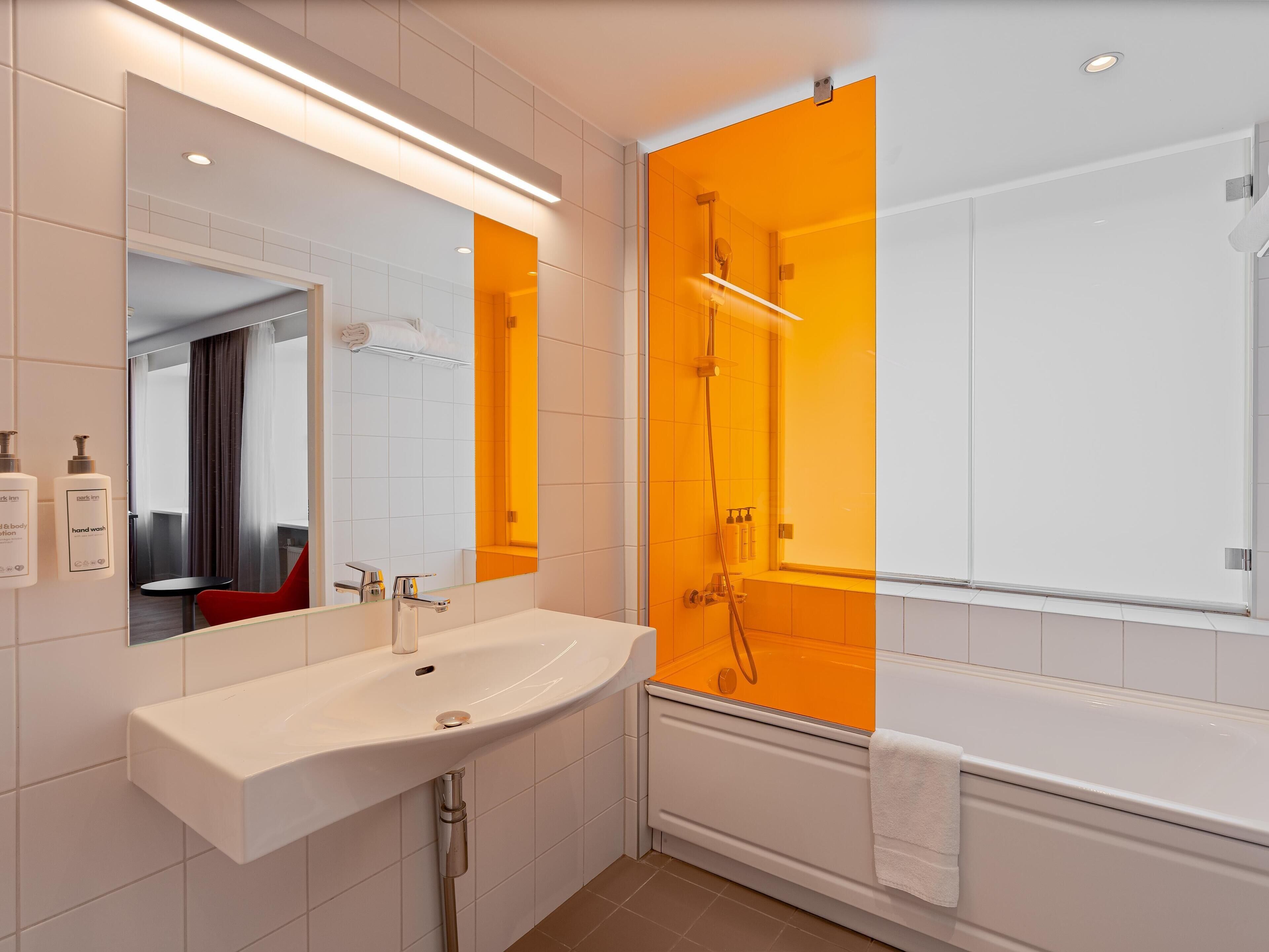 A modern bathroom with a white sink, a mirror, a shower, and a bathtub.