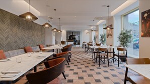 A modern dining area with multiple tables and chairs, a herringbone-patterned wall, and pendant lighting. - Park Inn by Radisson Meriton Conference & Spa Hotel Tallinn (Tallinn)