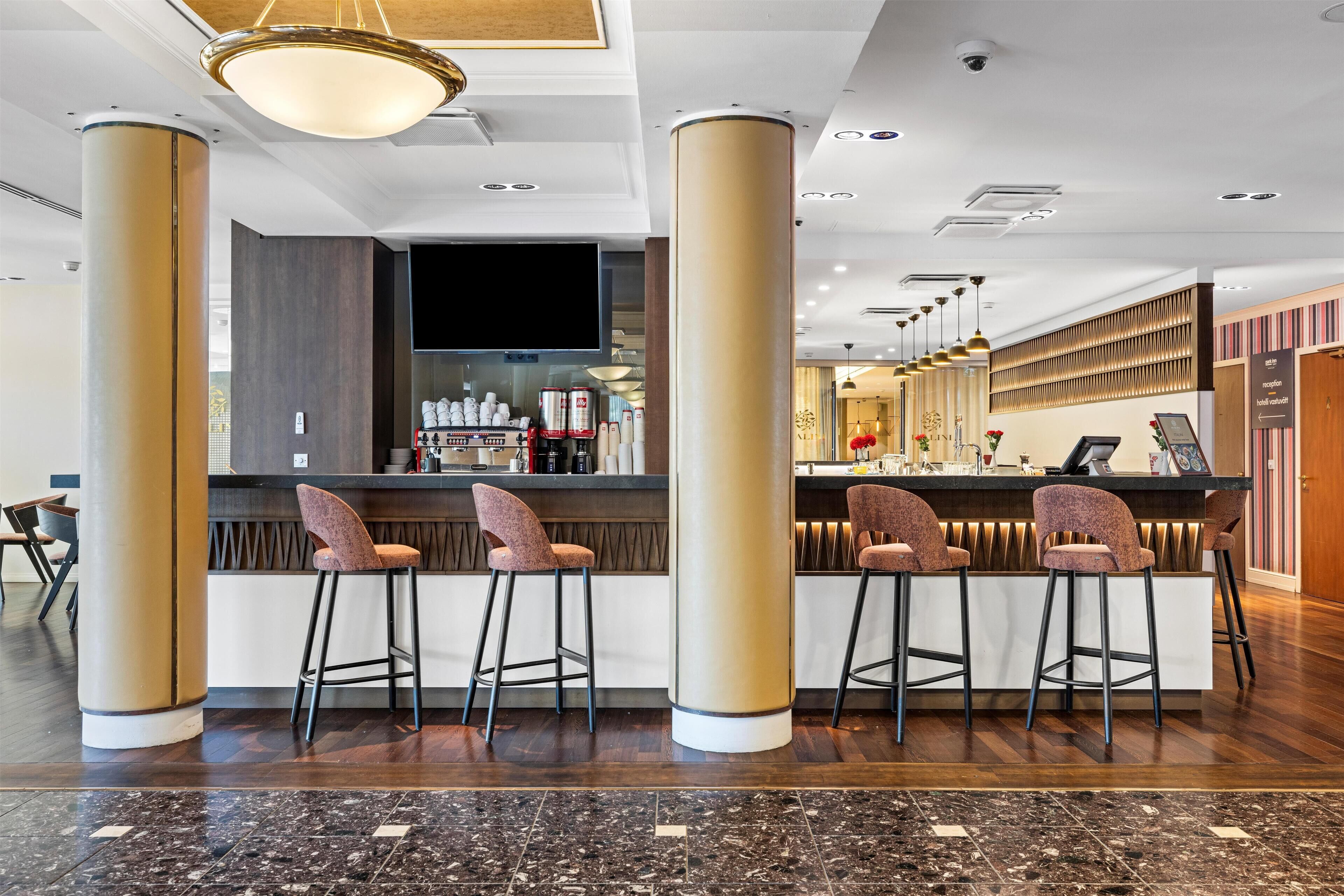 A modern bar area with high stools, a counter, and a television screen.