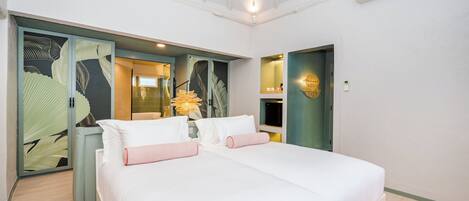 A hotel room with a large bed, a wardrobe, a mirror, and a small seating area with a lamp.