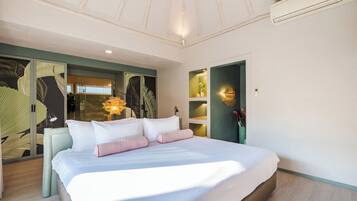 A modern hotel room with a large bed, a seating area with a chair, and a decorative wall with leaf patterns.