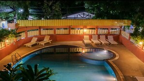 A nighttime view of a swimming pool with lounge chairs and a covered seating area. - Takiab Beach Resort (Hua Hin)