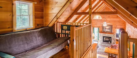 Ein gemütliches Holzblockhaus mit Schlafzimmer im Erkergeschoss, Kamin und Essbereich.