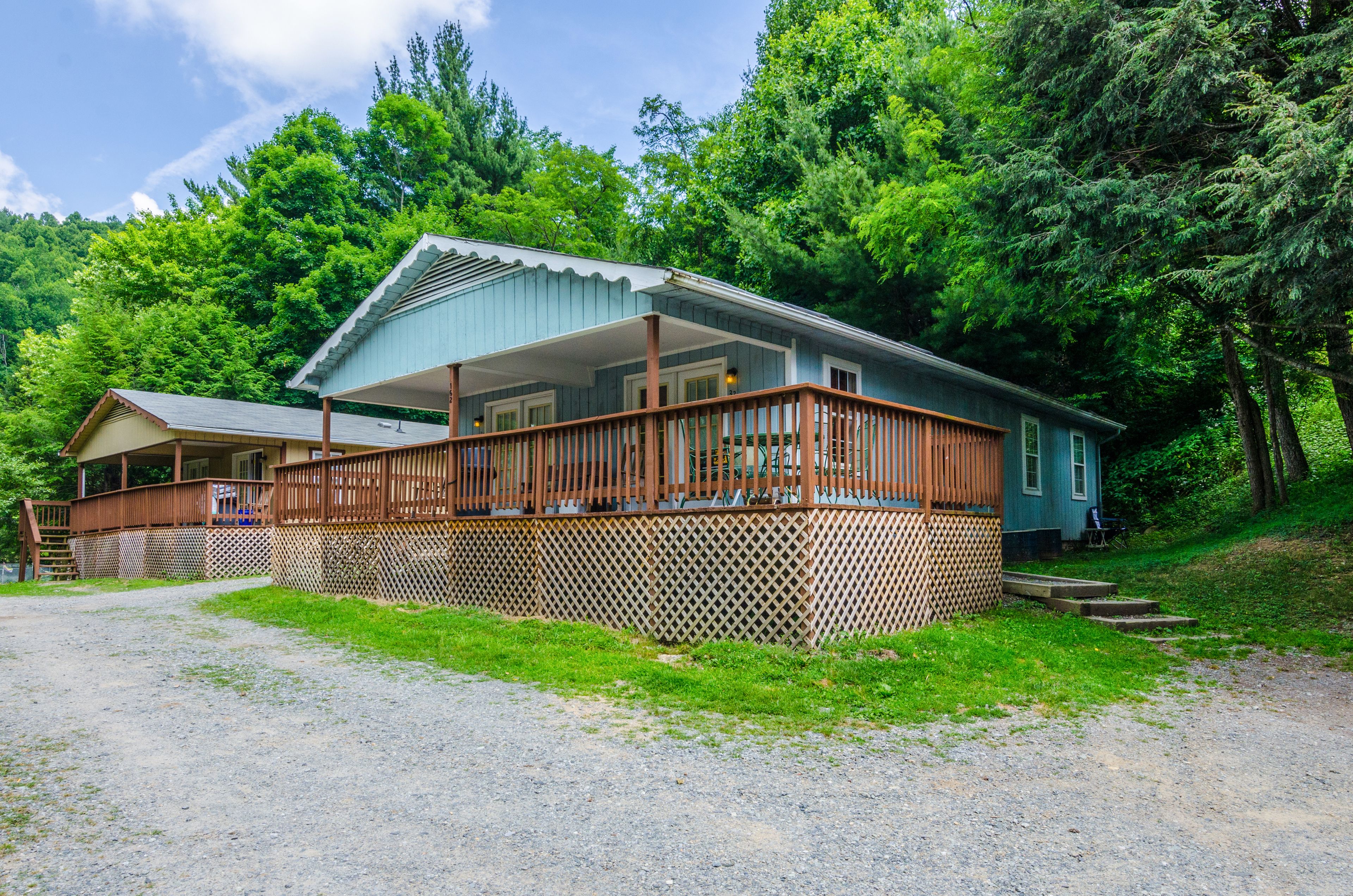 A two-story cabin with a wooden deck and a covered porch.