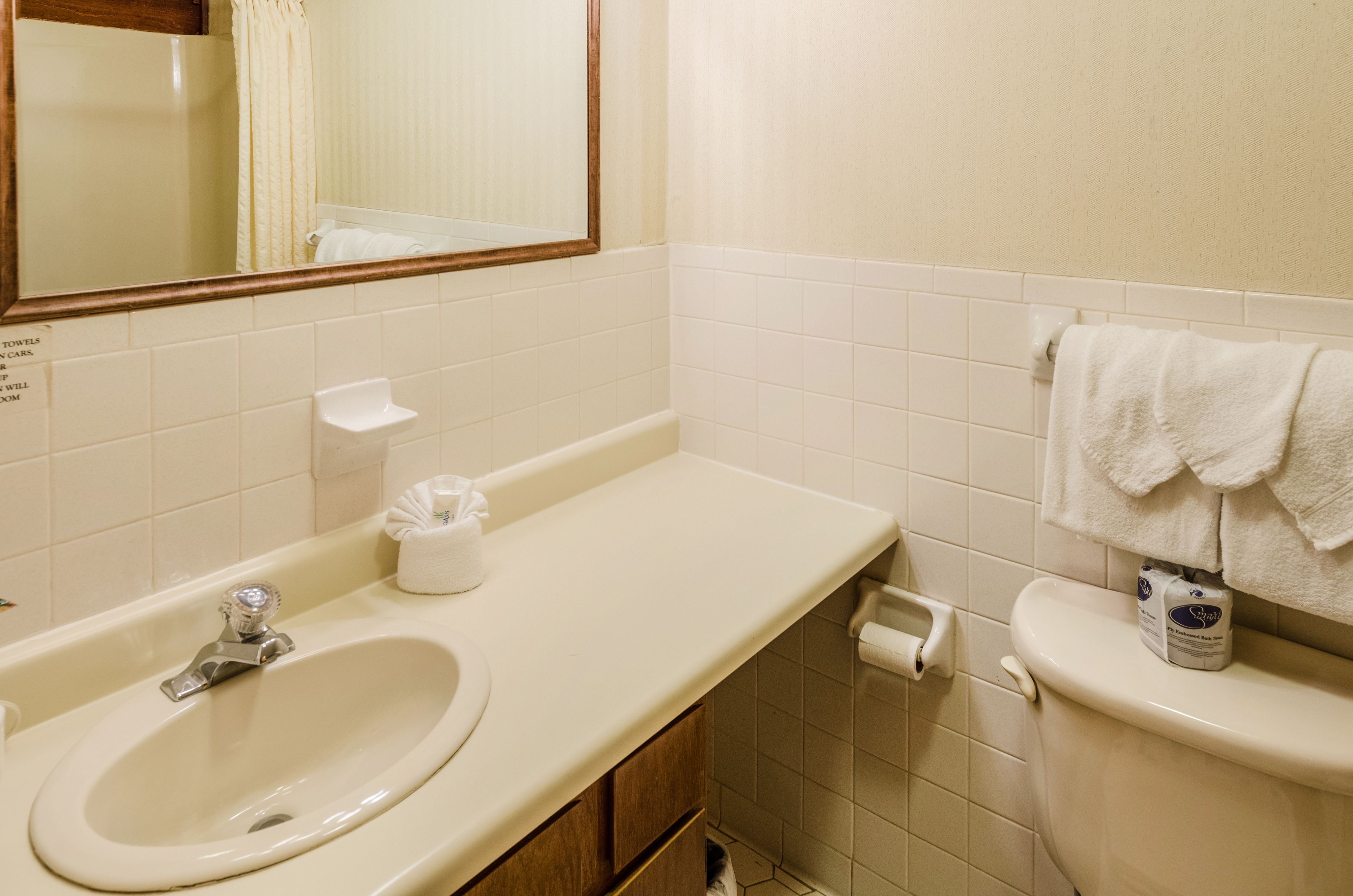 Une salle de bain équipée d’un lavabo, d’un miroir, de toilettes et d’un porte-serviettes.