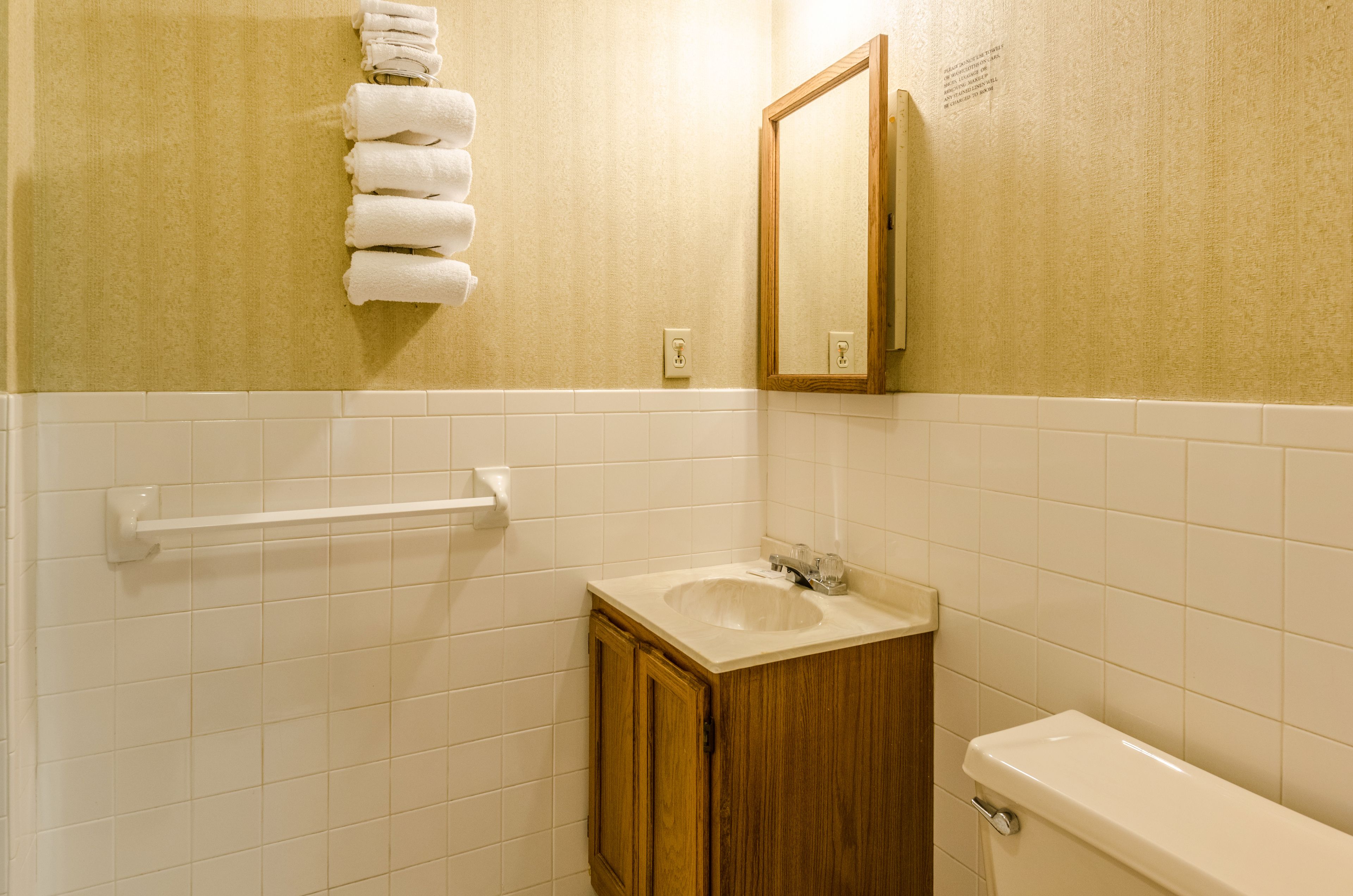 A bathroom with a sink, mirror, towel rack, and toilet.