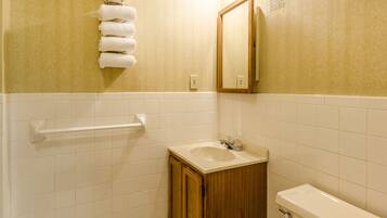 A bathroom with a sink, mirror, towel rack, and toilet.