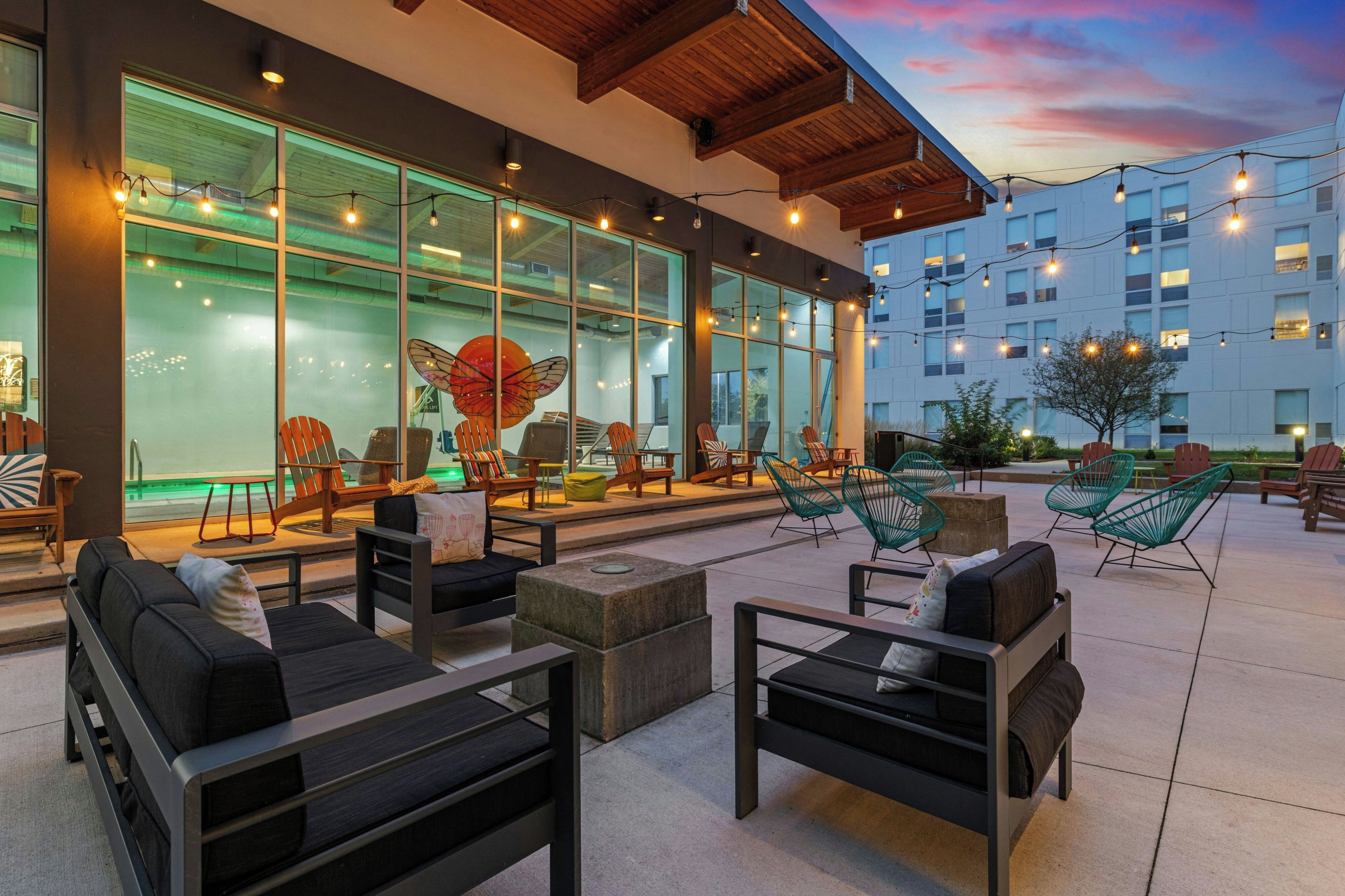 Un espacio al aire libre con mobiliario moderno, ventanas amplias y luces colgantes.