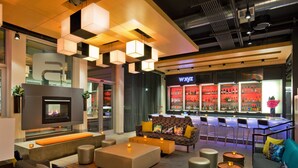 Un espacio lounge moderno con chimenea, asientos y un bar con iluminación roja.