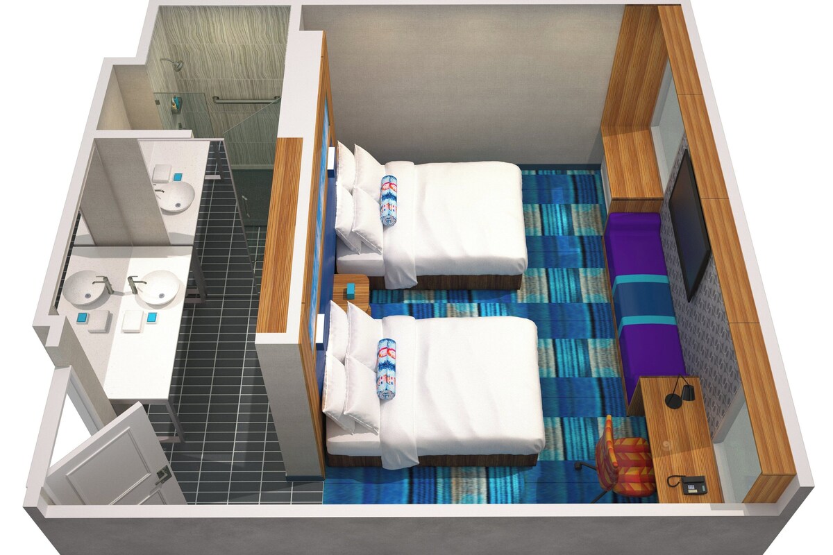 A hotel room with two beds, a bathroom, a small desk, and a TV.