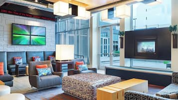 A modern lounge area with seating, a flat-screen TV, and a fireplace.