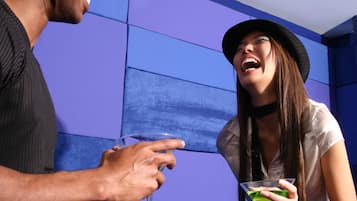 A man and a woman holding drinks in a room with blue walls.