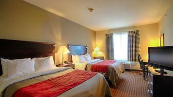 A hotel room with two beds, a desk with a computer, a chair, and a TV.