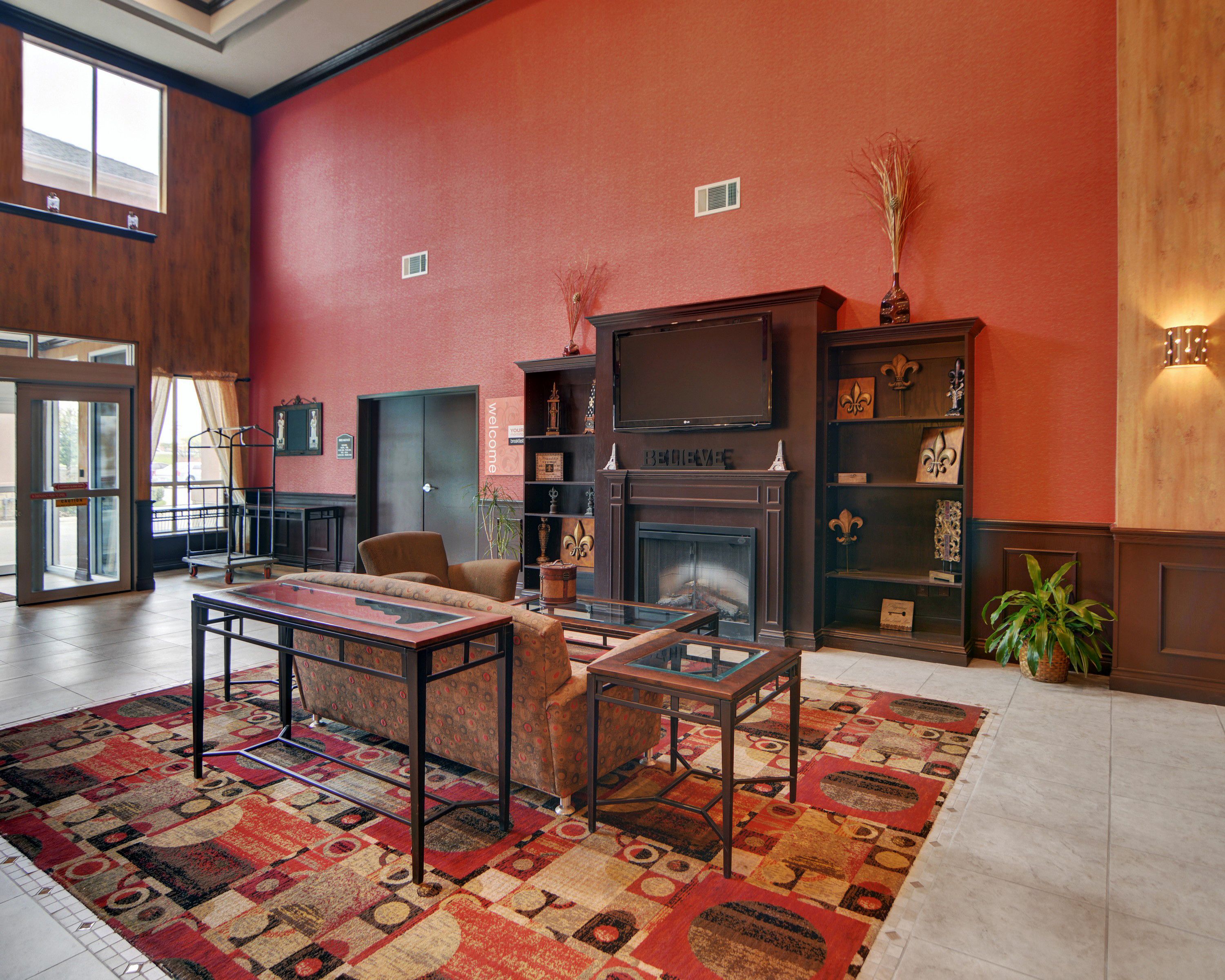A lobby with a fireplace, seating area, and a large window.