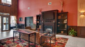 A lobby with a fireplace, seating area, and a large window.