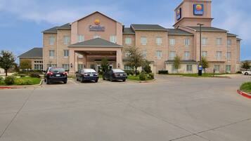 A Comfort Inn & Suites hotel with a brick facade, a covered entrance, and a parking lot with several cars.