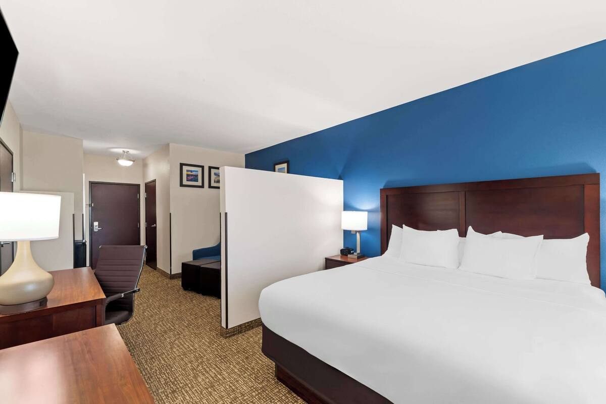 Ein Hotelzimmer mit einem großen Bett, einem Schreibtisch mit Lampe, einem Sessel und einem Kleiderschrank.