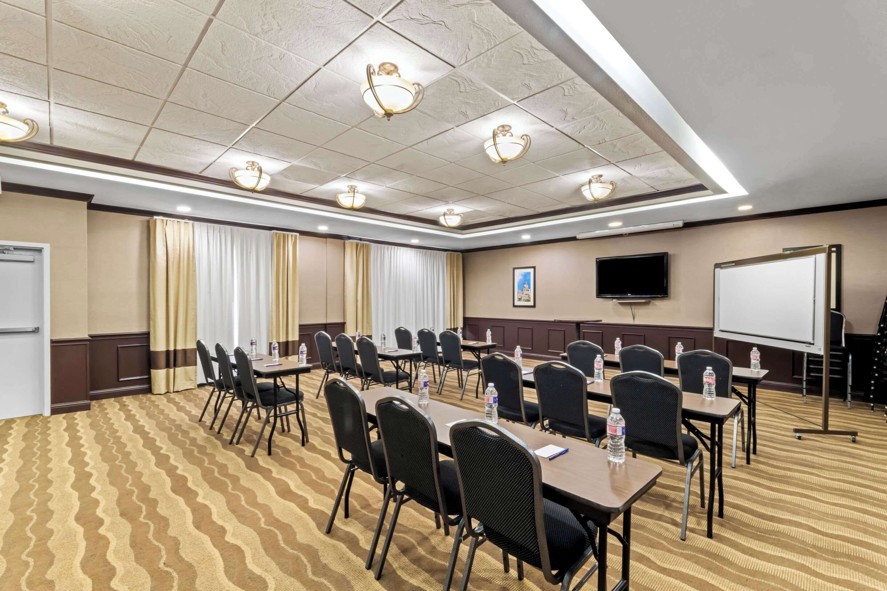 A conference room with tables and chairs, a whiteboard, and a projector screen.