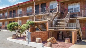 A multi-story motel with a brick facade, multiple balconies, and a parking lot.