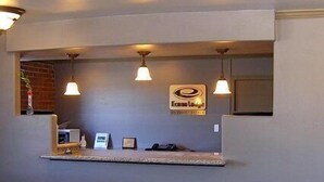 A reception desk with a sign reading "Econola Lounge" and a brick wall in the background.