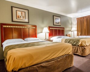 A hotel room with two beds, each with a wooden headboard, a bedside table with a lamp, and a framed picture on the wall. - Rodeway Inn Prescott (Prescott)