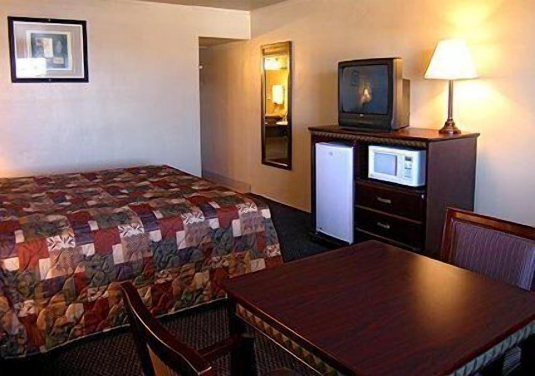 Une chambre d’hôtel équipée d’un lit, d’un bureau, d’une télévision, d’un réfrigérateur et d’une lampe.