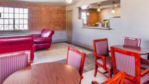 A dining area with a brick wall, red leather seating, and wooden tables and chairs.
