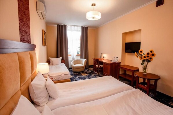 Une chambre d’hôtel avec deux lits, un bureau, une chaise, une télévision et un vase rempli de tournesols.