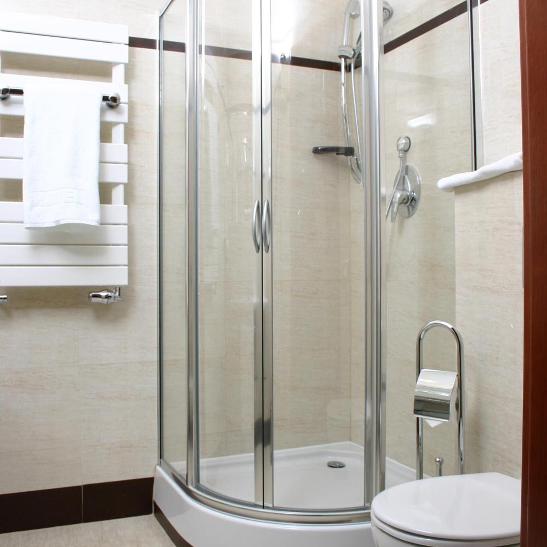 Une cabine de douche fermée par des parois en verre, avec des toilettes et un porte-serviettes.