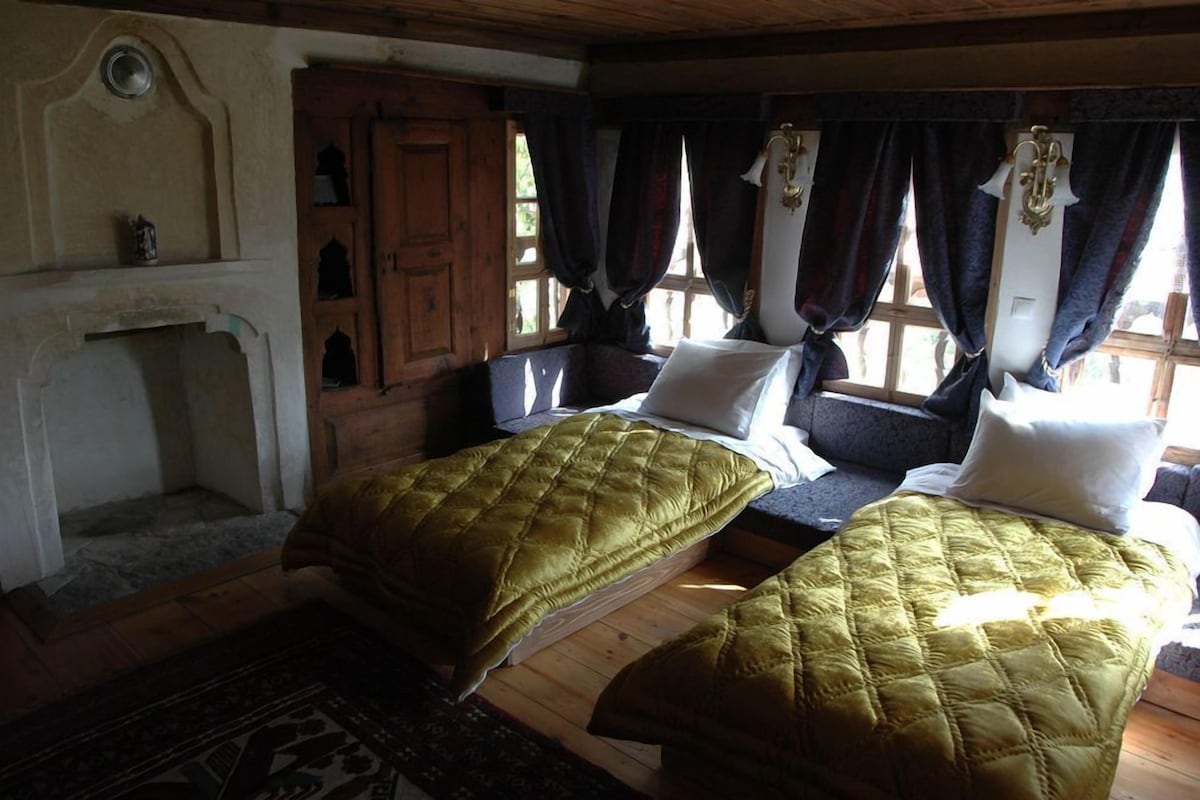 Une chambre avec deux lits, une commode en bois et une fenêtre avec des rideaux.