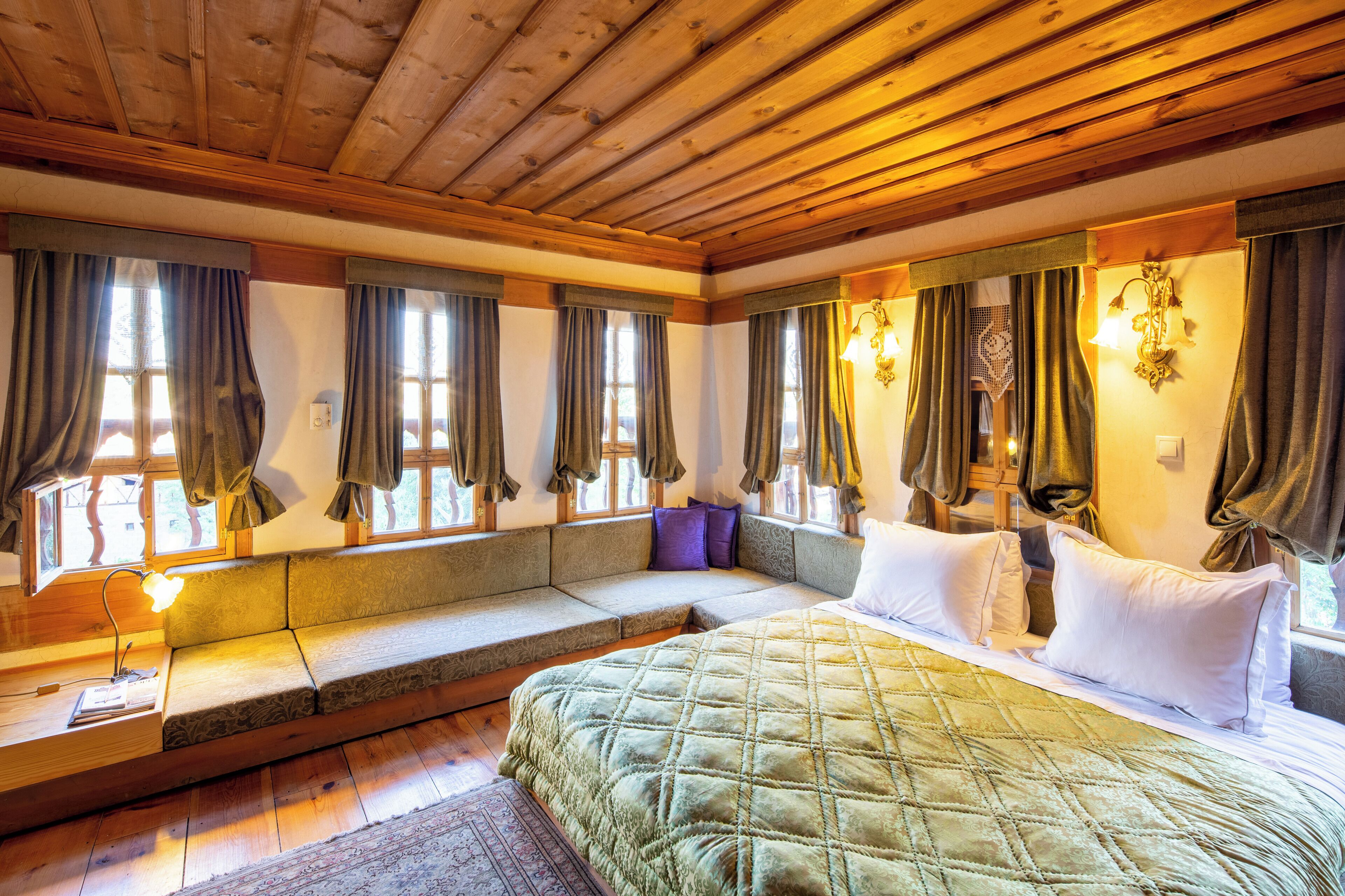 A cozy bedroom with a large bed, a built-in bench, and a window with curtains.