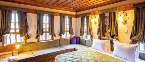 A cozy bedroom with a large bed, a built-in bench, and a window with curtains.