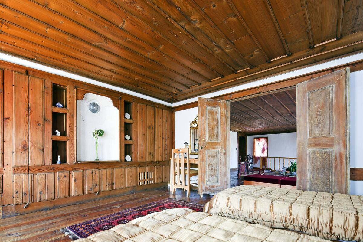 Una habitación rústica de madera con una cama, estanterías y un escritorio con espejo.
