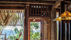 Ein rustikales Holzinnere mit einem großen Fenster, einer Tür, die nach draußen führt, und einem Tisch mit einer Lampe.