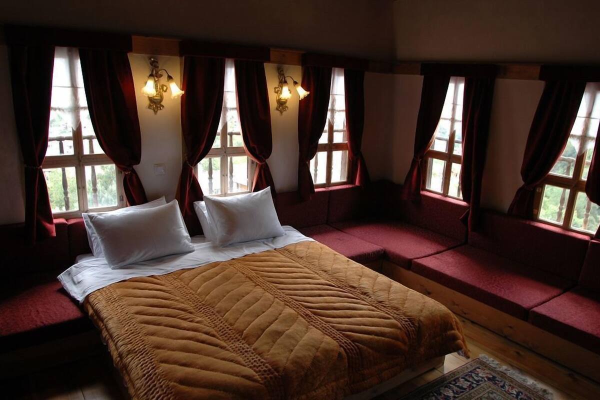 Una habitación con cama, cortinas rojas y ventana con vistas.