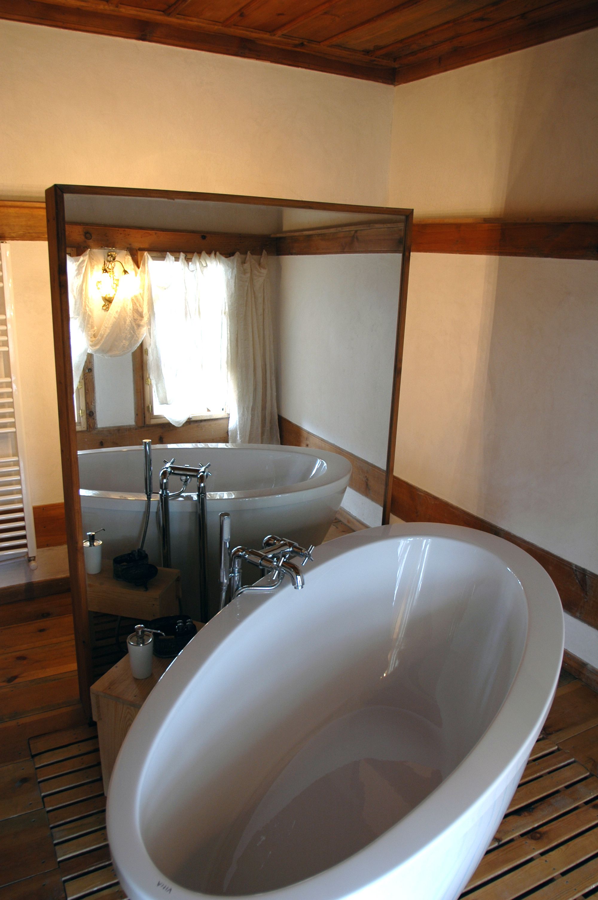 A bathroom with a large bathtub, a sink, and a mirror.