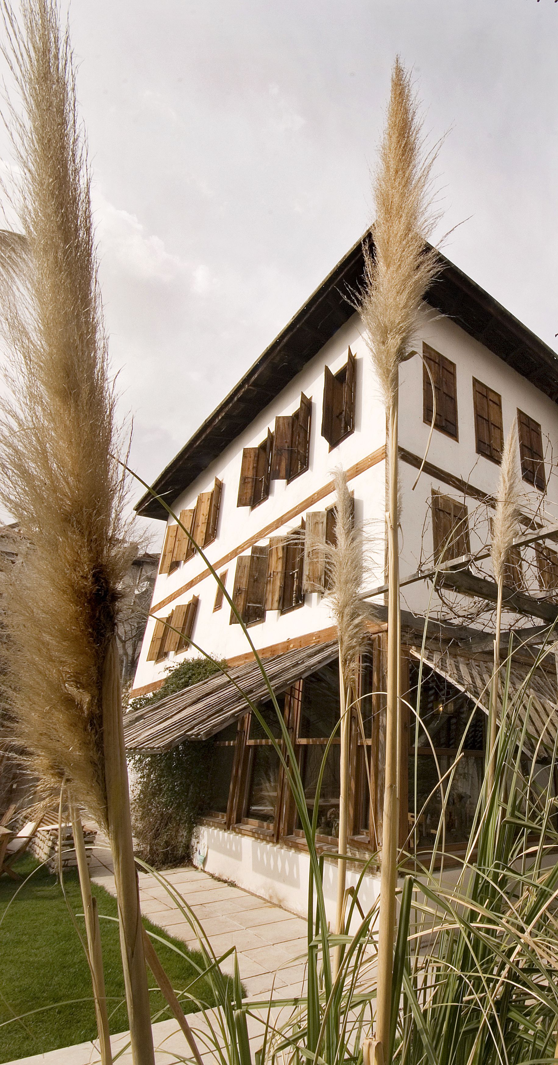 A traditional two-story building with wooden shutters, a sloped roof, and a visible balcony.