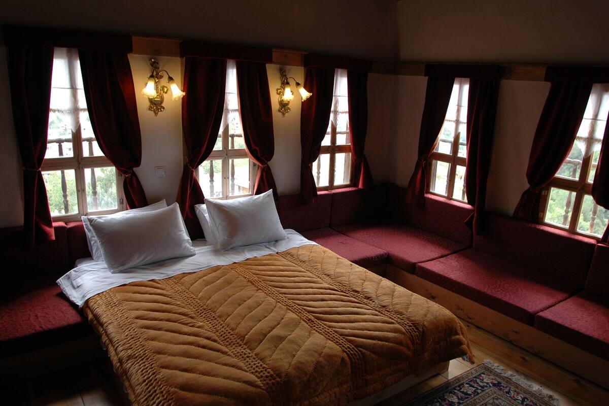 Un dormitorio con una cama grande, cortinas rojas y ventana con vistas a zonas verdes.