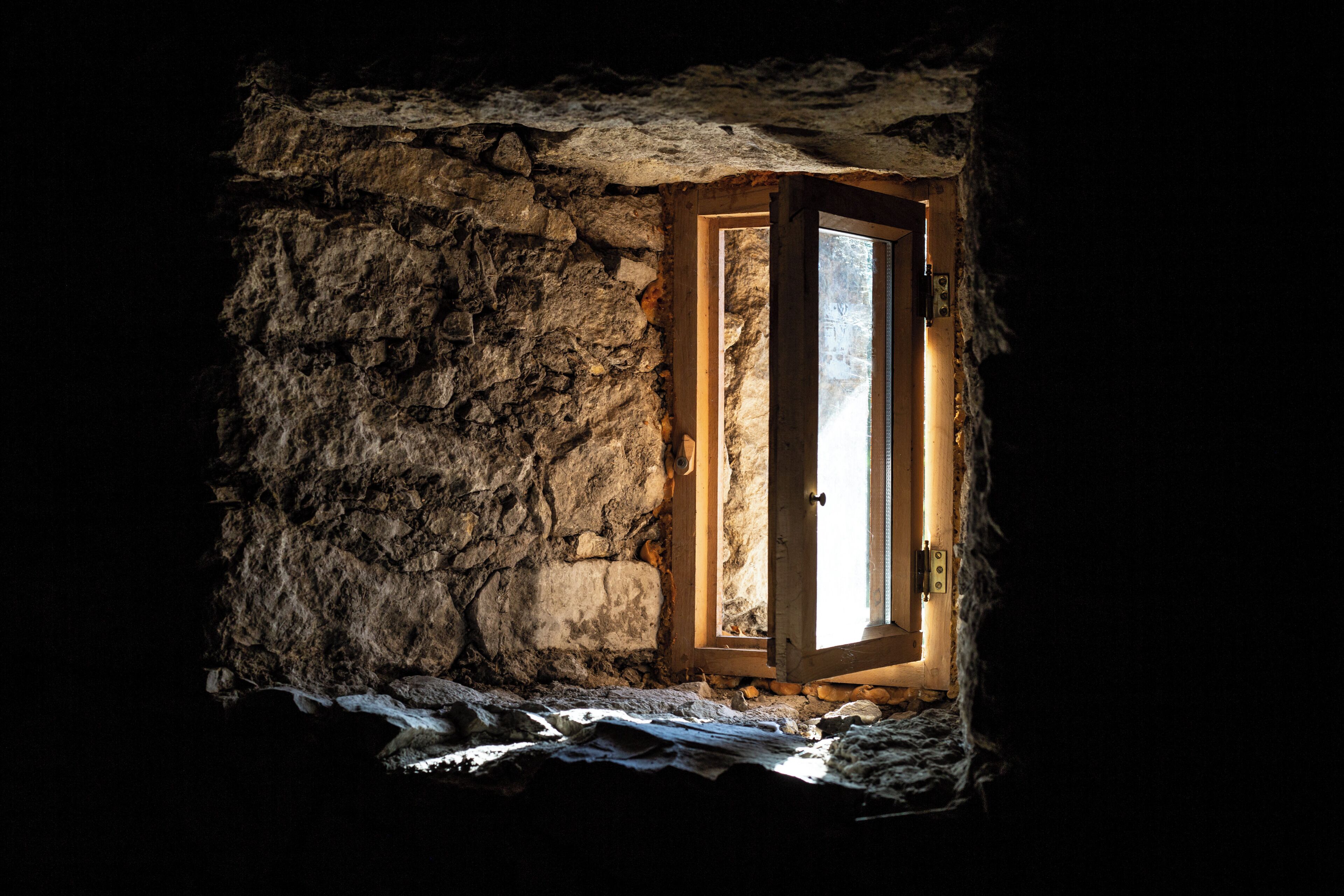Un muro de piedra con una puerta y ventana de madera, que ofrece vistas al exterior.