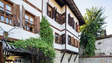Ein traditionelles Gebäude mit steinernen Fundament, Holzbalken und einem Balkon mit roten Stühlen.