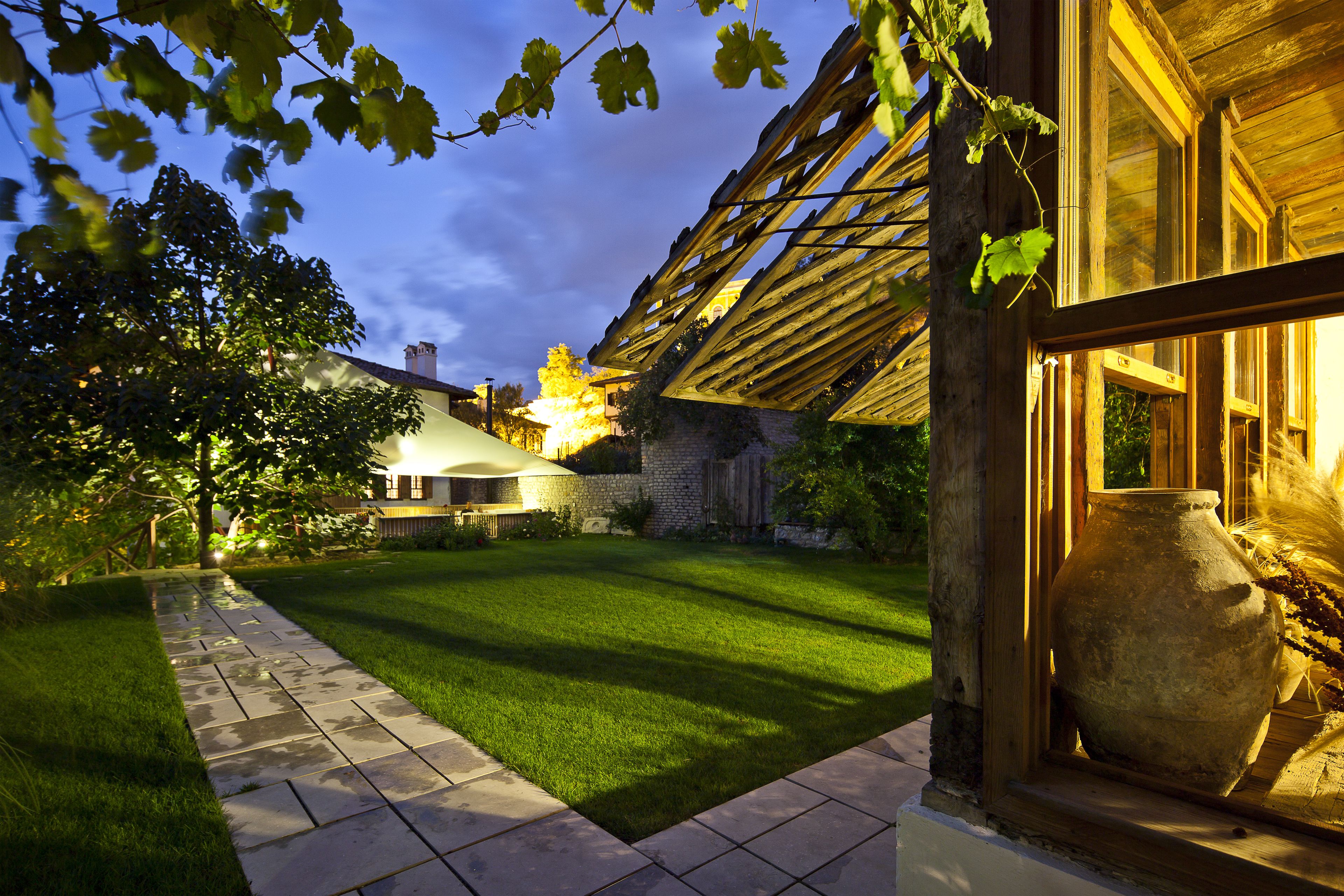 A well-maintained garden with a paved pathway, a stone wall, and a large window with a view of the garden.