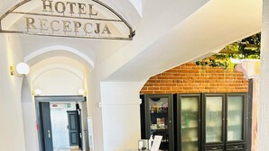 Un espace d’accueil d’hôtel comprenant un comptoir de réception, une poubelle et un présentoir à magazines.