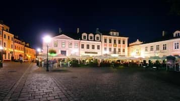 Une place pavée, bordée de bâtiments historiques, avec des terrasses et des lampadaires.