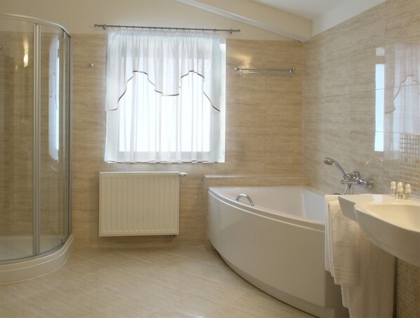 A modern bathroom with a glass shower enclosure, a freestanding bathtub, and a vanity with a sink and mirror.