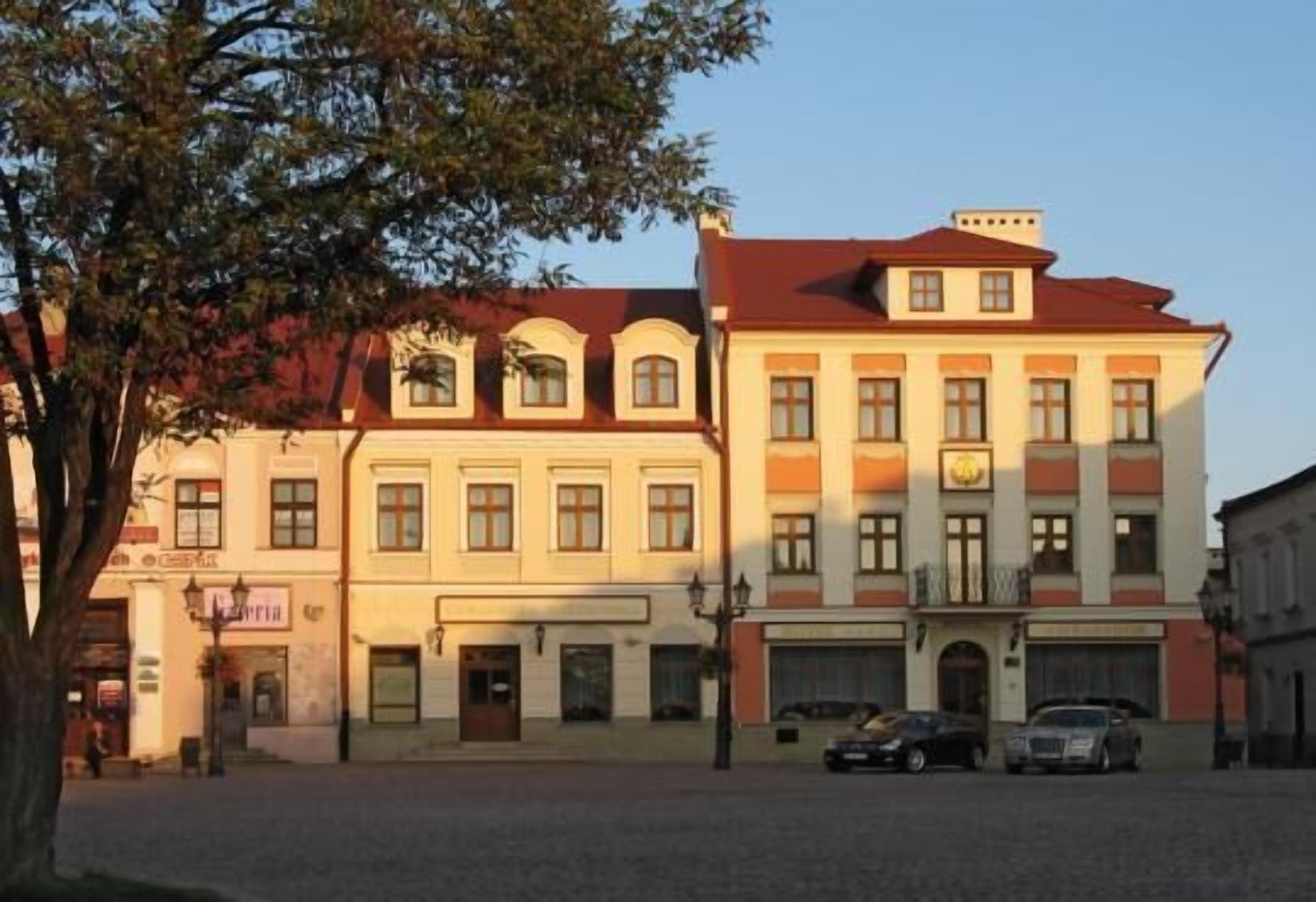 A building with a red roof, multiple windows, and a tree in the foreground.