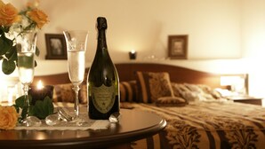Une table avec une bouteille de champagne, deux verres et un vase rempli de roses, dans une chambre d’hôtel.